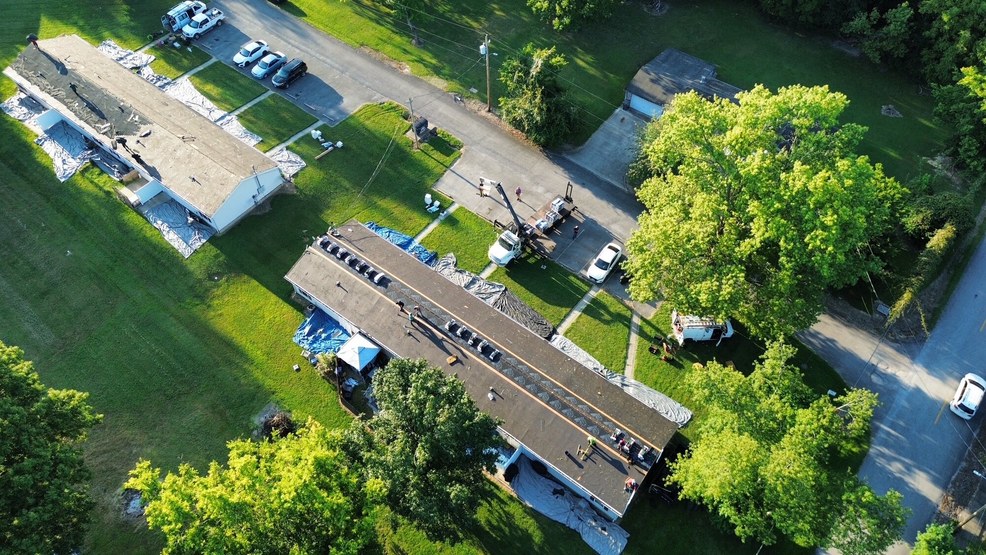 Roofing crew and equipment beside a residential project